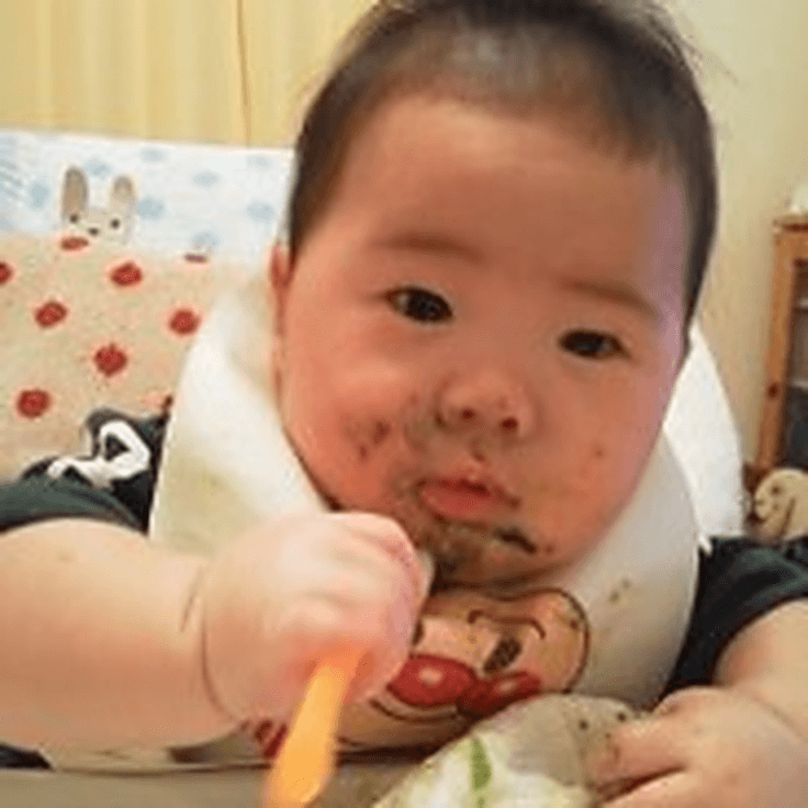 スプーンを自分で持って食べようとする離乳中期の子ども